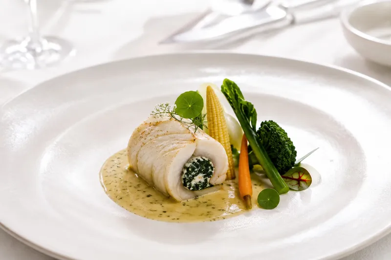 Rolled Thai sea bass stuffed with spinach and amaranth cheese, served with seasonal vegetables and a light sauce