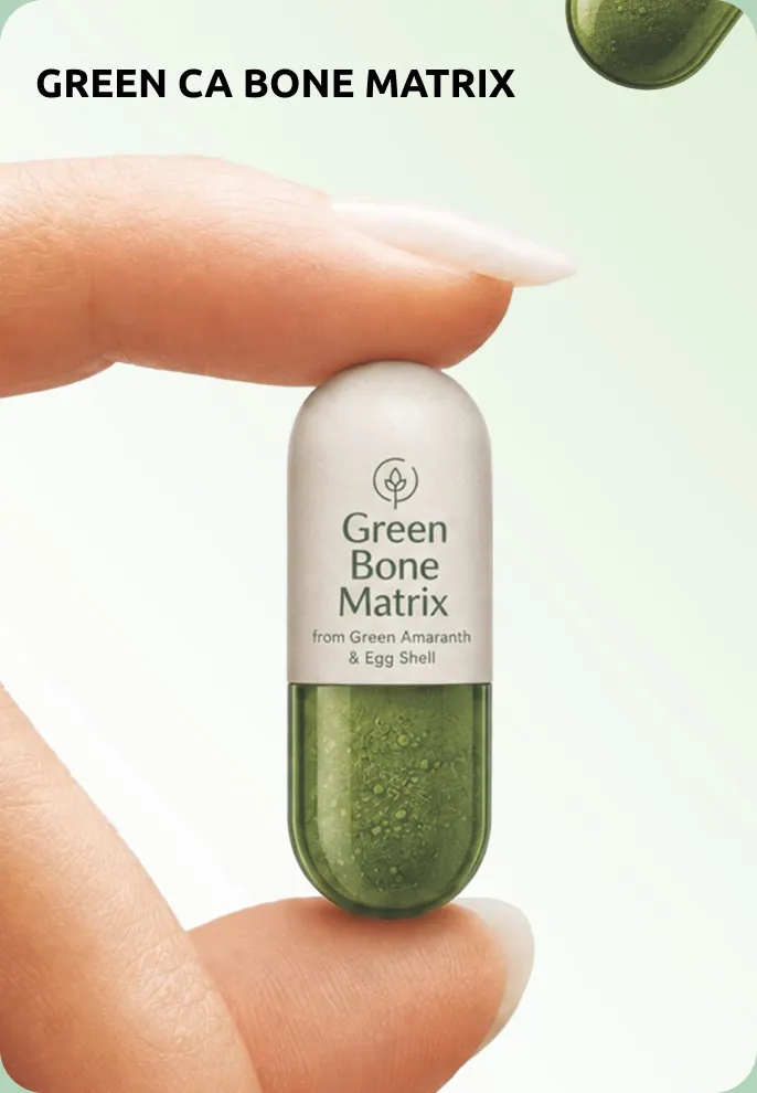 Fingertips holding a green Green CA Bone Matrix capsule