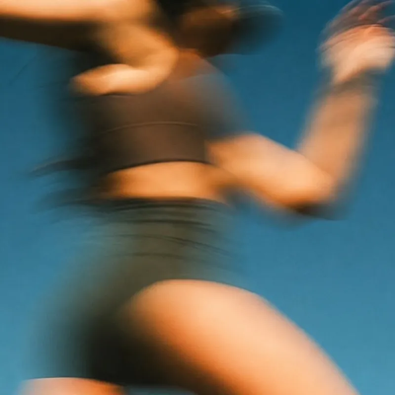 A woman exercising, blurred in motion against blue water